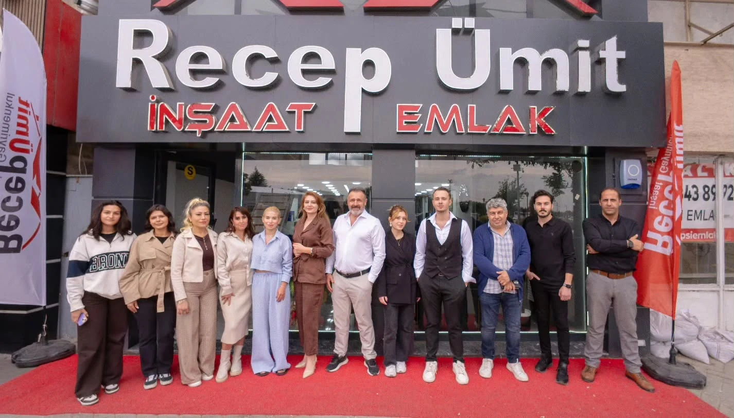 A group photograph in front of the Recep Ümit İnşaat Emlak sign